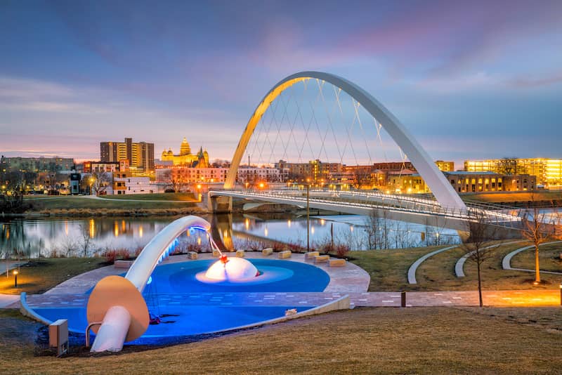Bridge leading to downtown Des Moines with large art installation of fishing pole and water.